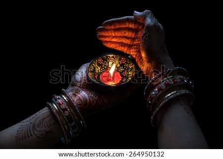 Woman hands with henna holding candle isolated on black background with clipping path 