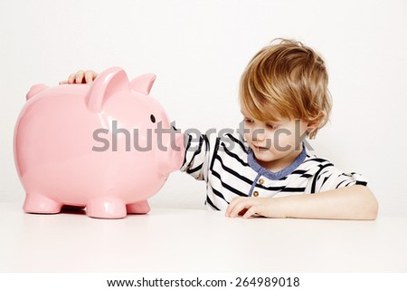 Young boy looking at large piggy bank
