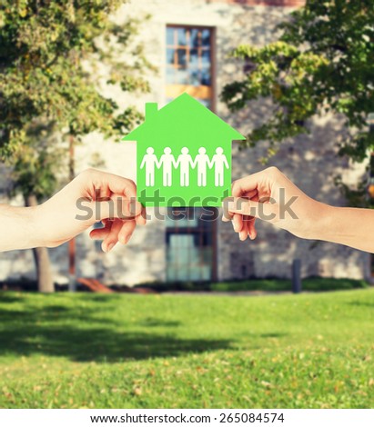 real estate and family home concept - isolated closeup picture of male and female hands holding green paper house