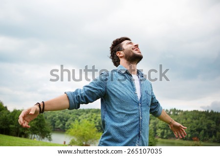 Emotional young man laughing in wind Royalty-Free Stock Photo #265107035