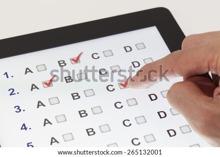 Finger clicking on a tablet with multiple-choice questions