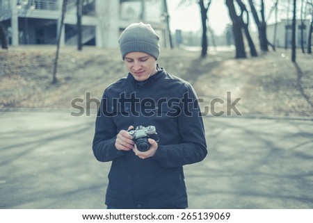Closeup of young  man with digital camera outdoors. Young male photographer photographing nature