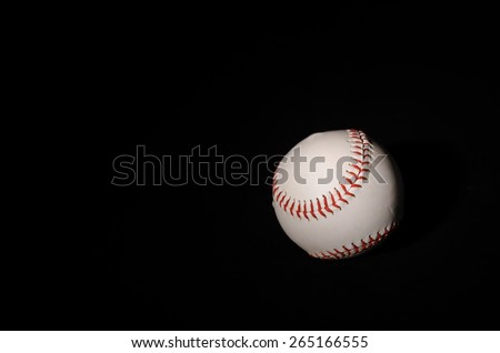 A single baseball on a black backdrop with single light illuminating it for isolation and drama.