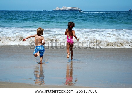 Picture of boy and girl racing to swim at the beach during the day. 