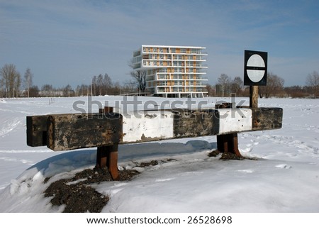 modern house behind of railway sign, middle of landscape at winter