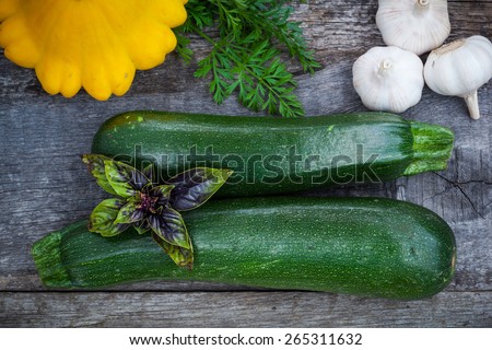 Fresh green zuchinni, squash with basil leaves and garlic on wooden board, top view