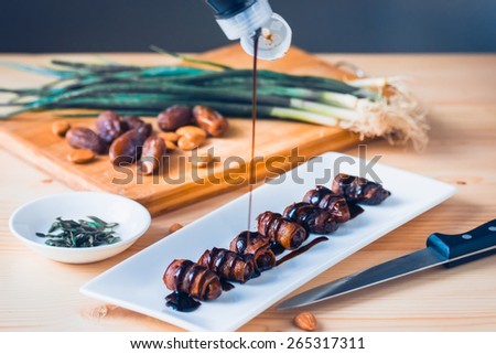 Snack appetizer - dried dates wrapped with bacon and dressed with balsamic creme vinegar. Toned picture