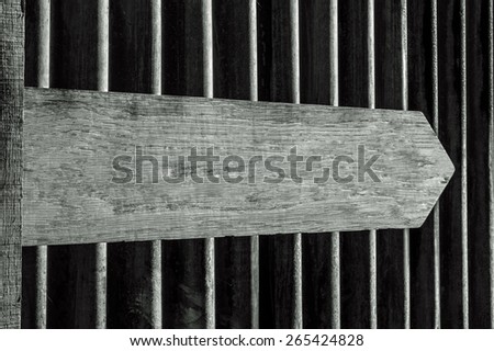 Blank Wooden Directional Sign against Corrugated Iron Background in Black and White. Copy space on pointer; potential use as a slide in a PowerPoint presentation.
