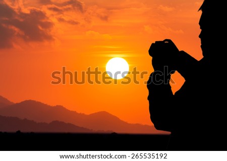 silhouette of young man photographing at sunset range