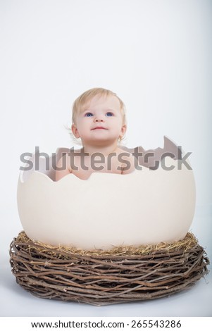cute beautiful emotional baby sitting in easter egg with nest  on white background