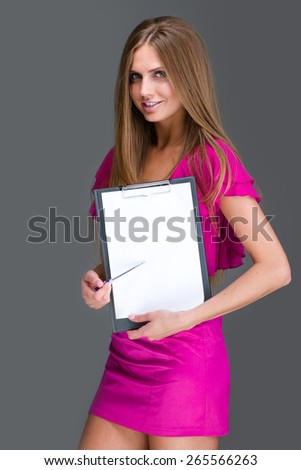 Smiling young business woman showing blank signboard, over gray background