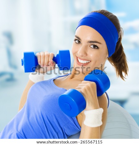 Portrait of happy smiling young beautiful woman exercising, at fitness club or center