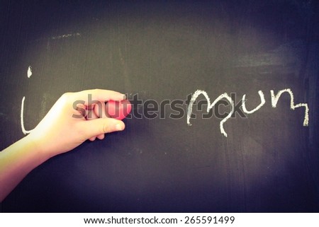 I heart Mum written on a blackboard with a child's hand holding a love heart