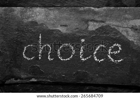 The word CHOICE written with chalk on black stone