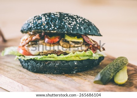 Modern black burger on wooden board. Toned picture