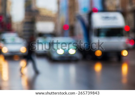 out of focus picture of city traffic with crossing people on a rainy day at dawn