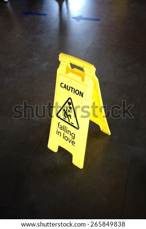Caution yellow sign for warning, falling in love, on a floor