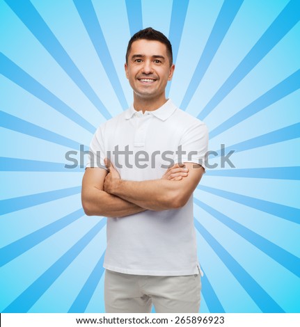 happiness and people concept - smiling man in white t-shirt with crossed arms blue burst rays background