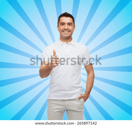 happiness, gesture and people concept - smiling man showing thumbs up blue burst rays background