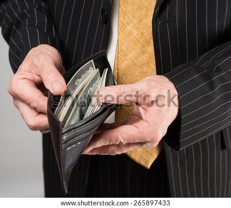 Businessman with money in purse in hands on a gray background