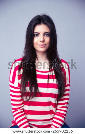 Portrait of a charming young woman over gray background. Looking at camera