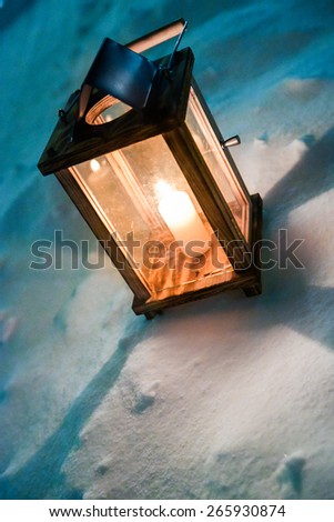Single candle light lantern standing in snow