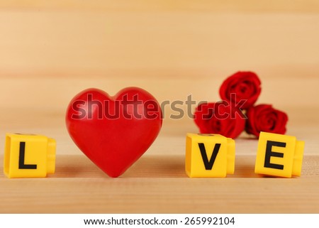 Decorative letters forming word LOVE with flowers and heart on wooden background