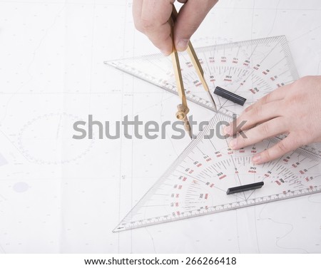 man drawing on ship map with divider and triangles