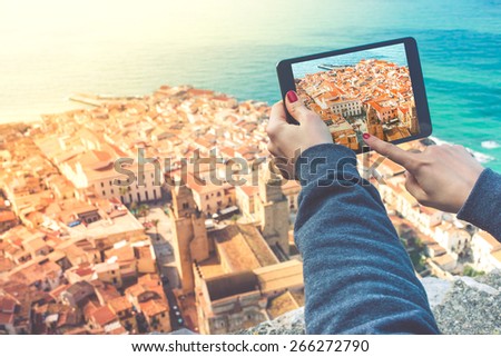 Person with tablet makes pictures of old city from the hill. Toned image