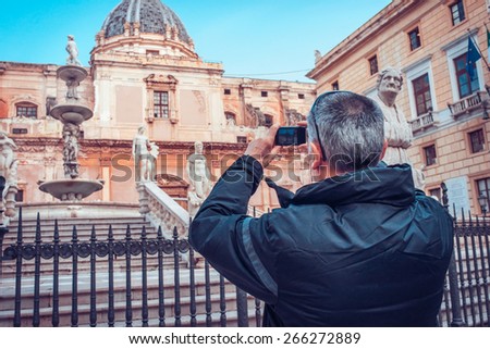 Tourist taking photo of famous Camilliani's fountain in Piazza della Pretoria in Palermo, Sicily island, Italy. Toned image