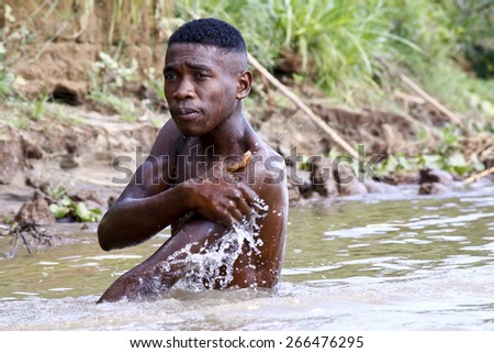 African poor man taking a bath in river, Madagascar