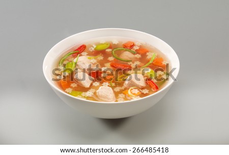 A plate of chicken soup on grey background