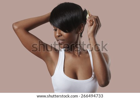 woman combing her short shiny hair on a pink