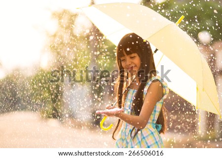 Pretty young asian girl in the rain with umbrella