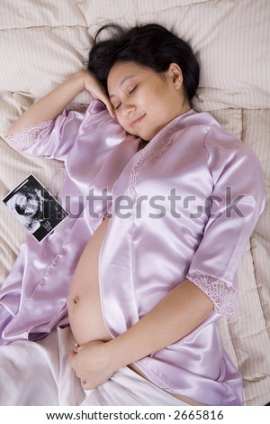 Pregnant woman sleeping with the ultrasound picture sitting next to her