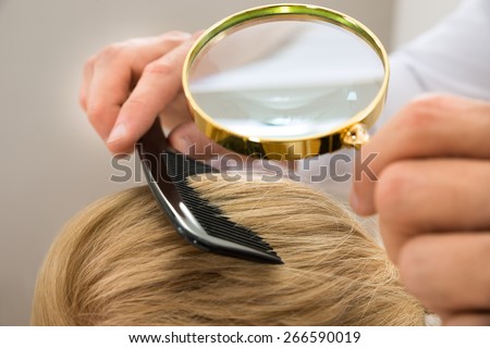 Close-up Dermatologist Looking At Patient's Blonde Hair Through Magnifying Glass