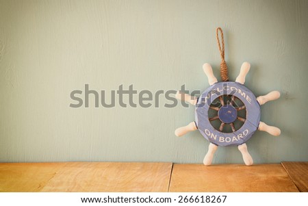 old nautical wood wheel on wooden table over wooden background. vintage filtered image

