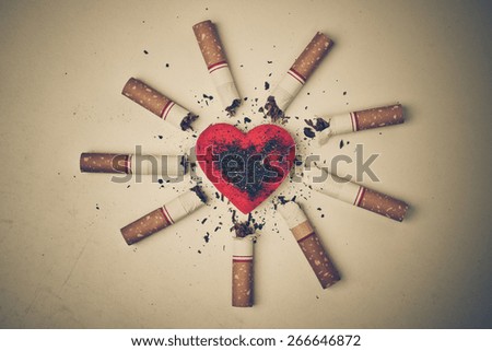 burnt cigarettes around a red heart / cigarette destroying health