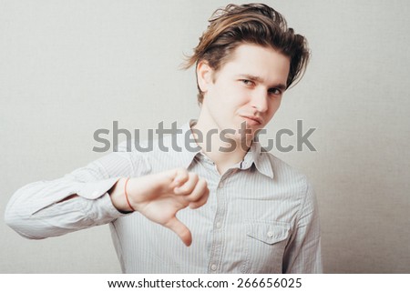young man showing thumbs down on a gray background