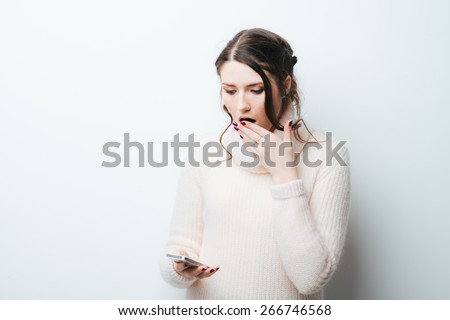 on a white background frightened girl looks at the phone
