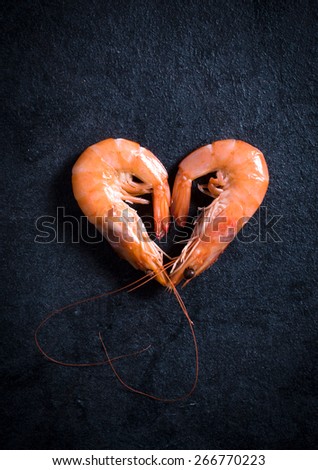 Heart shape boiled tiger shrimps on dark background with blank space
