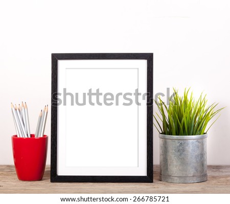 picture frame with office items and pot plant on wooden table