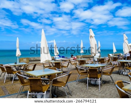 Tables and umbrellas on the sea coast. Cafe on the beach