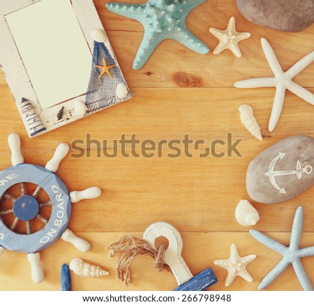 collection of nautical and beach objects creating a frame over wooden background,