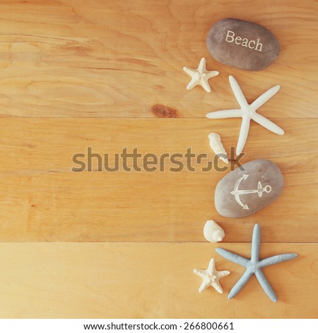 collection of nautical and beach objects creating a frame over wooden background, 