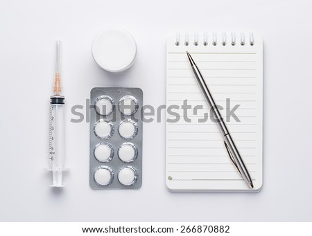 Modern workplace with a note, pen, pills and syringes. Medicine concept. View from above