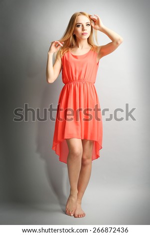 Expressive young model in orange dress on gray background