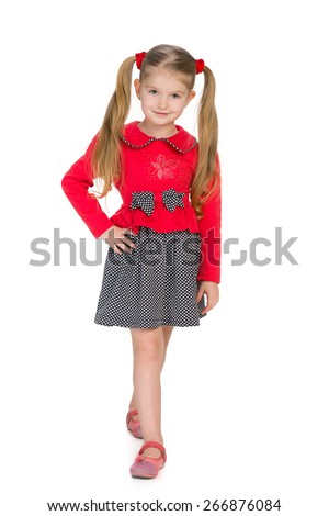 A smiling fashion little girl is walking against the white background