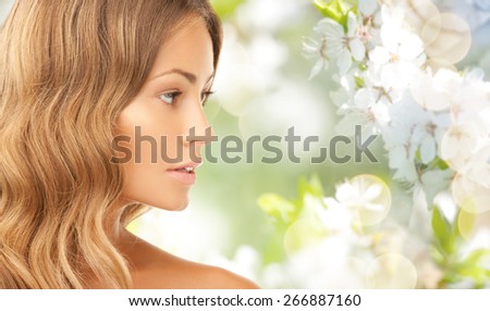 beauty, people, summer, spring and health concept - beautiful young woman face over green blooming garden background