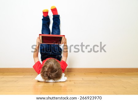 little boy looking at touch pad at home Royalty-Free Stock Photo #266923970